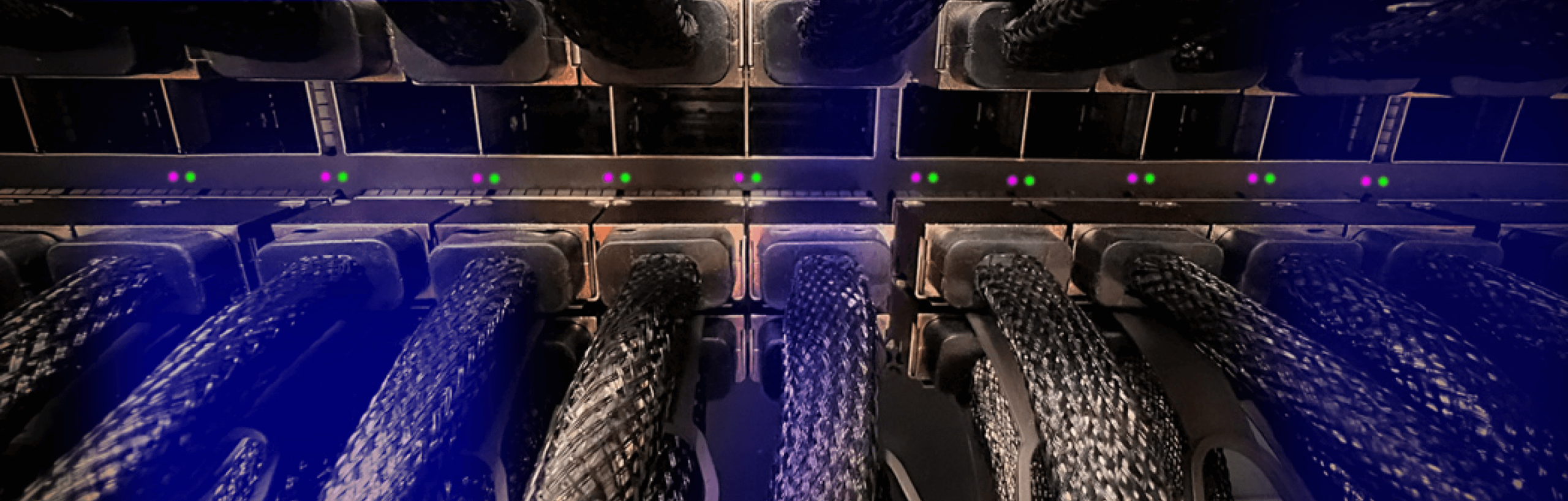 Close-up view of data cables connected to a server rack, with colored indicator lights glowing, highlighting the complexity and infrastructure of data management and network connectivity in a data center environment.